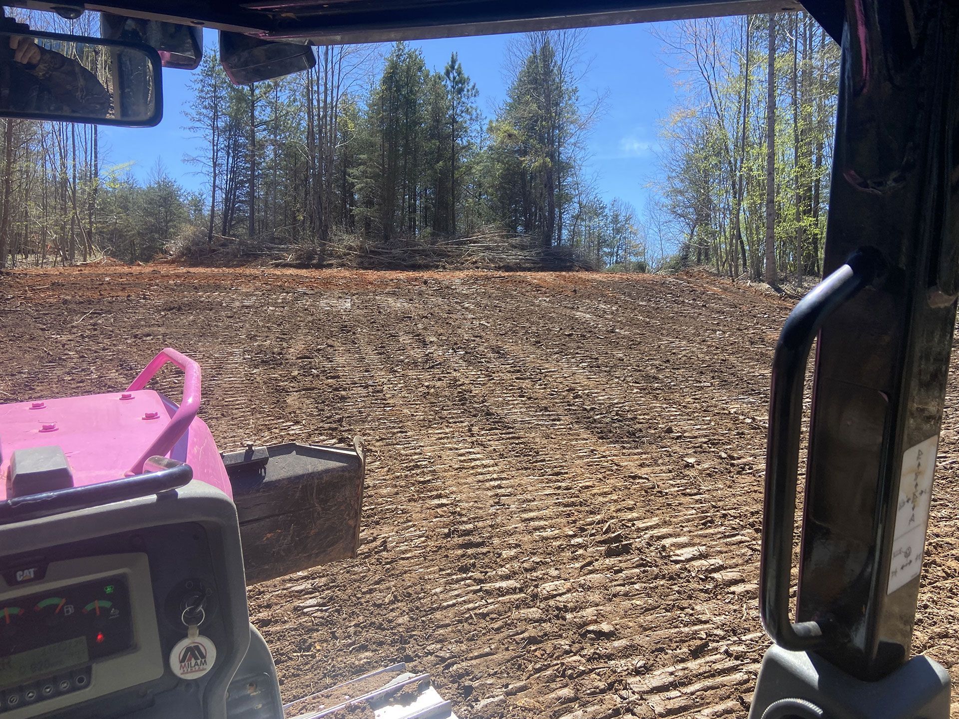 View from a cab driving across a muddy forest clearing with a pink dashboard panel visible