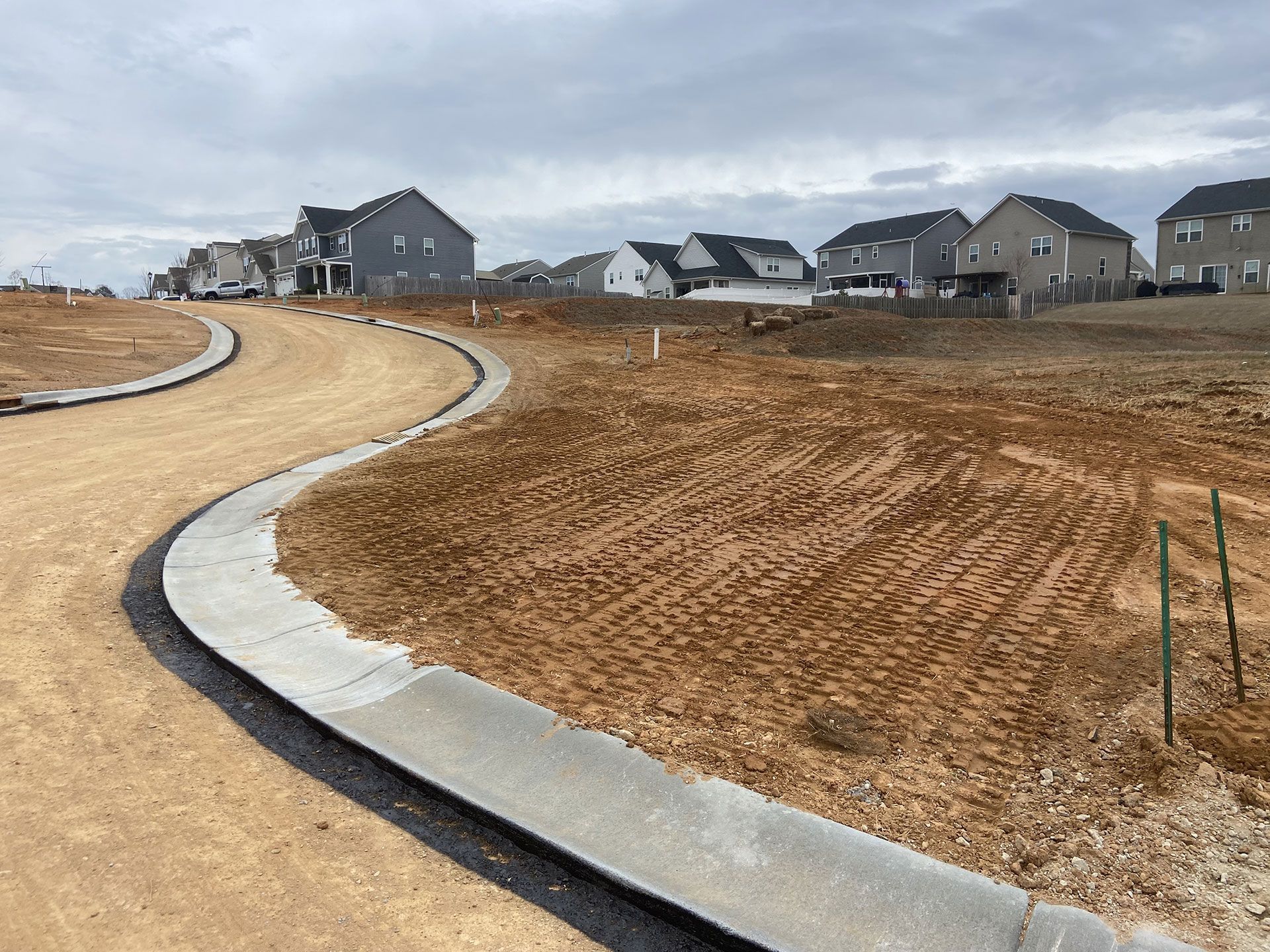 Curving concrete sidewalk through a new residential subdivision with homes and bare earth