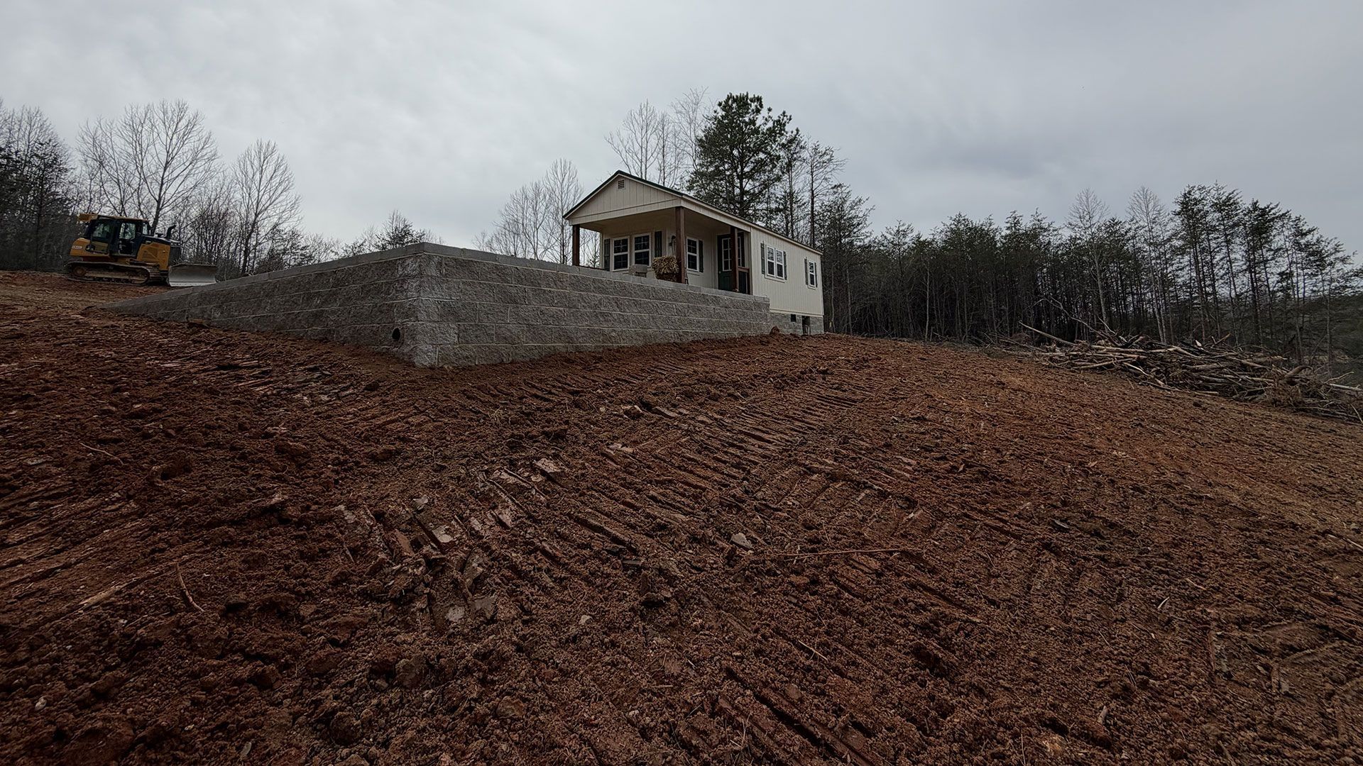 Small white house on a hill above a brown, leaf-covered field under cloudy skies