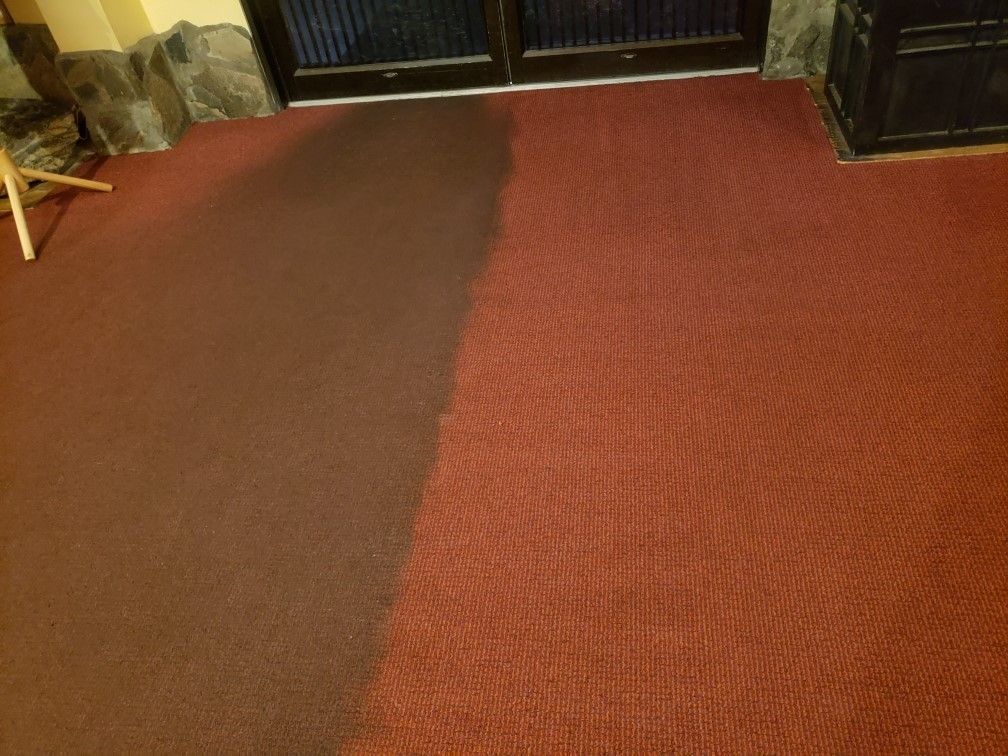 A red carpet is being cleaned in a room.