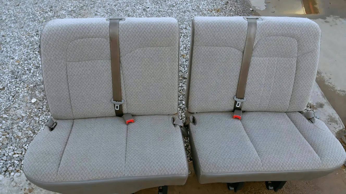a pair of seats with seat belts attached to them are sitting on top of a pile of gravel
