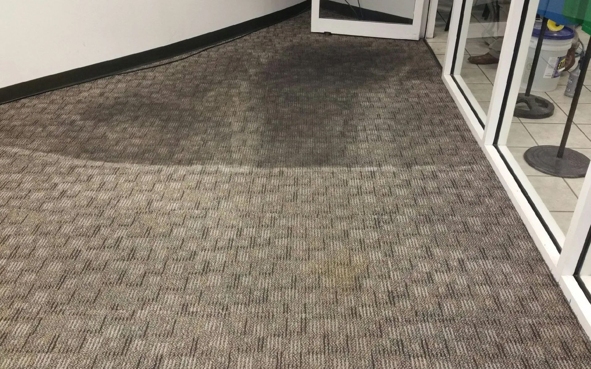 A dirty carpet in a room next to a window