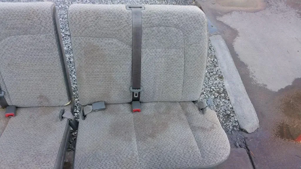 A car seat with a seat belt attached to it is sitting on the ground