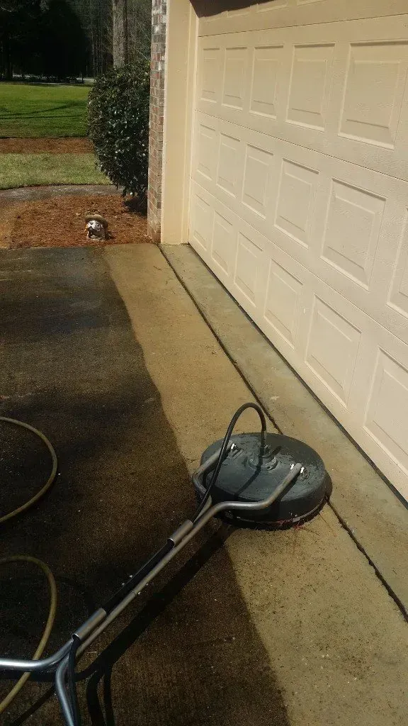 A machine is cleaning a driveway next to a garage door