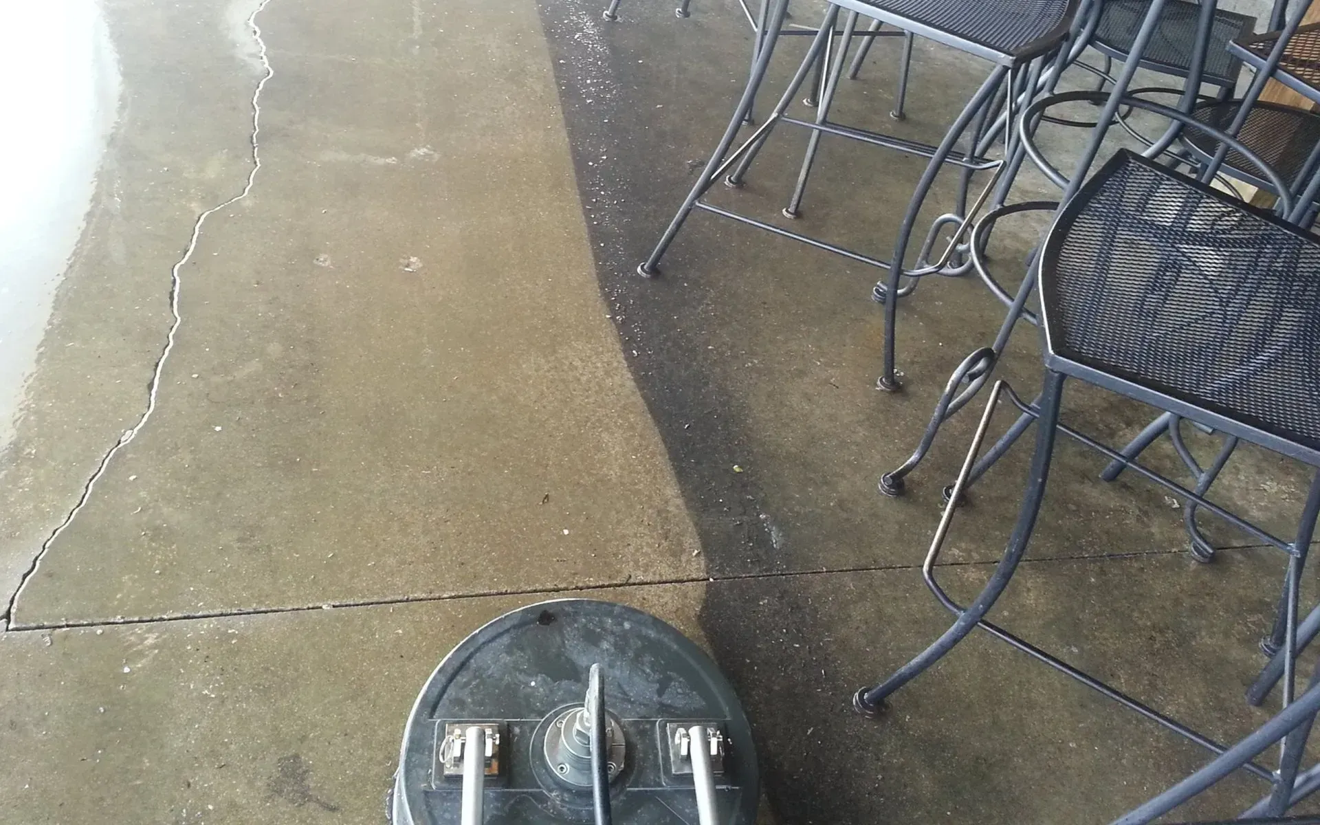 A vacuum cleaner is cleaning a patio with tables and chairs