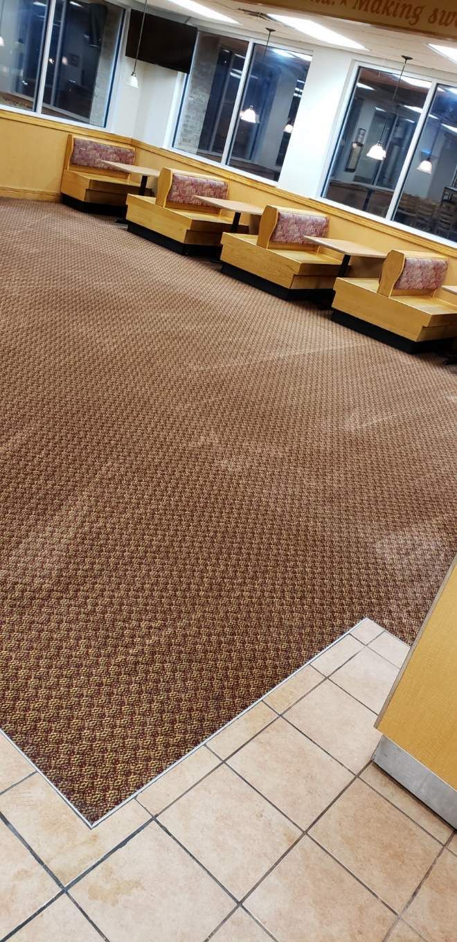 A restaurant with tables and chairs and a brown carpet on the floor