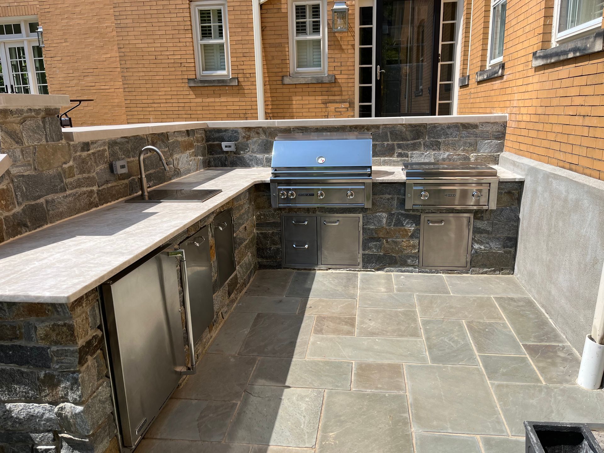 A kitchen with a grill and a sink in front of a brick building.