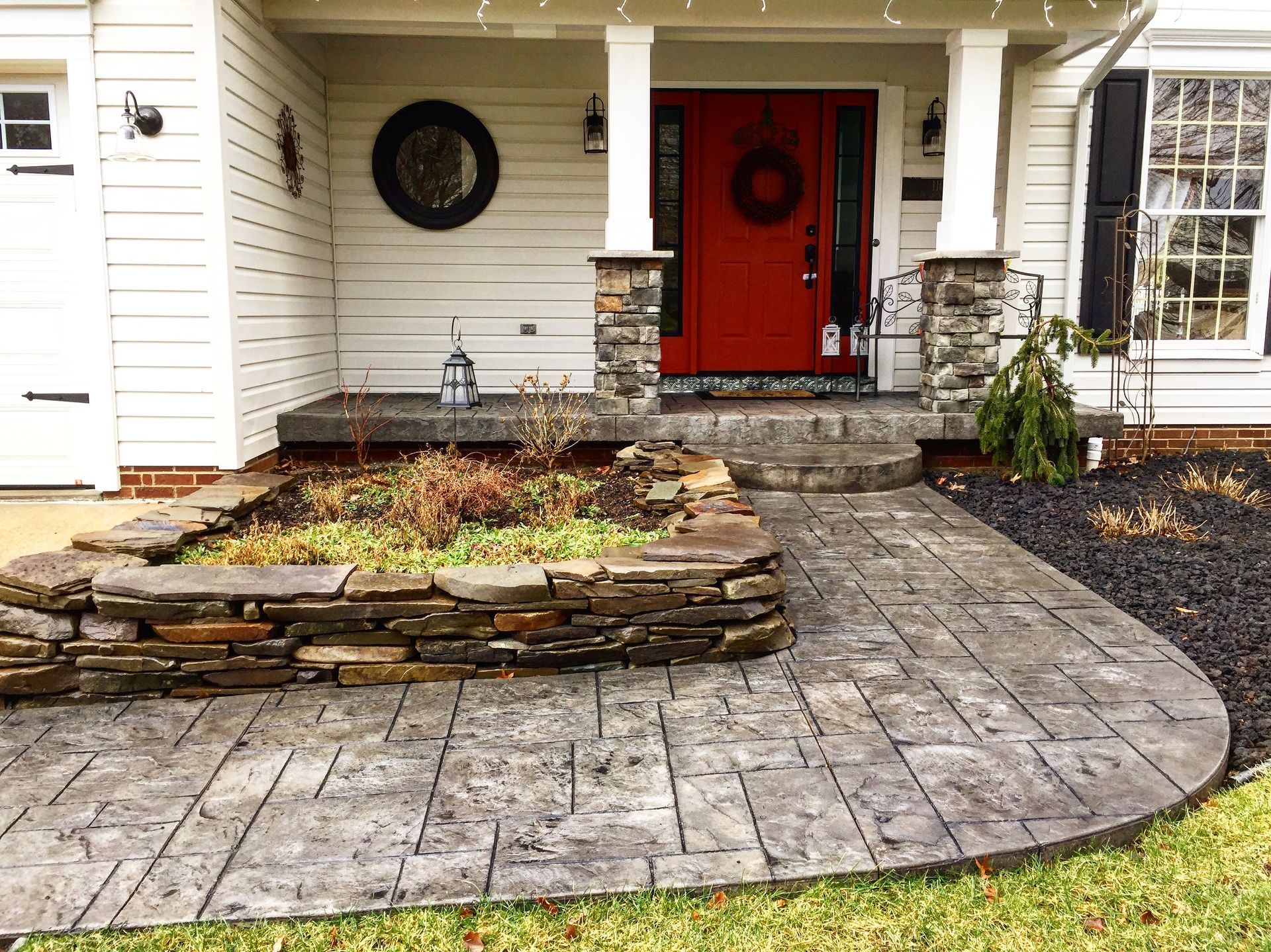 A white house with a red door and a stone walkway leading to it.