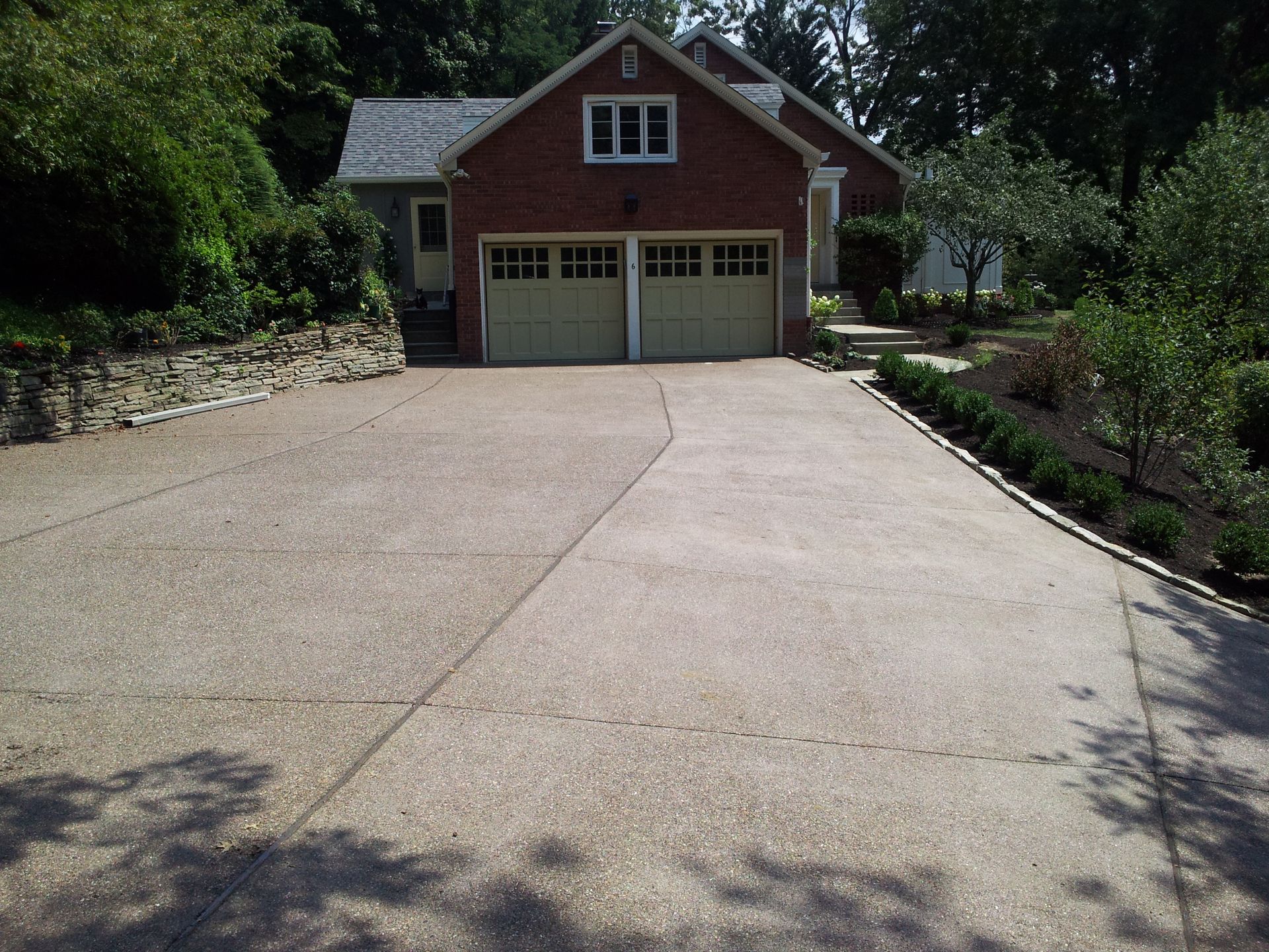 A driveway leading to a brick house with two garage doors