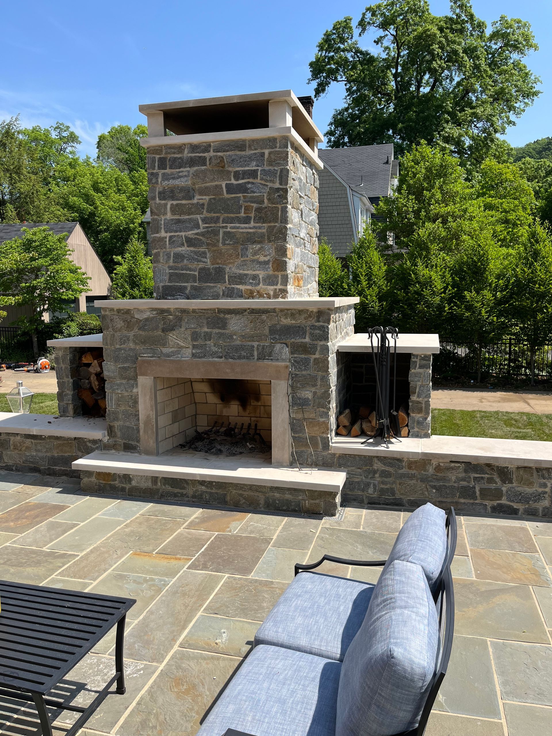 A stone fireplace is sitting on a patio next to a couch.