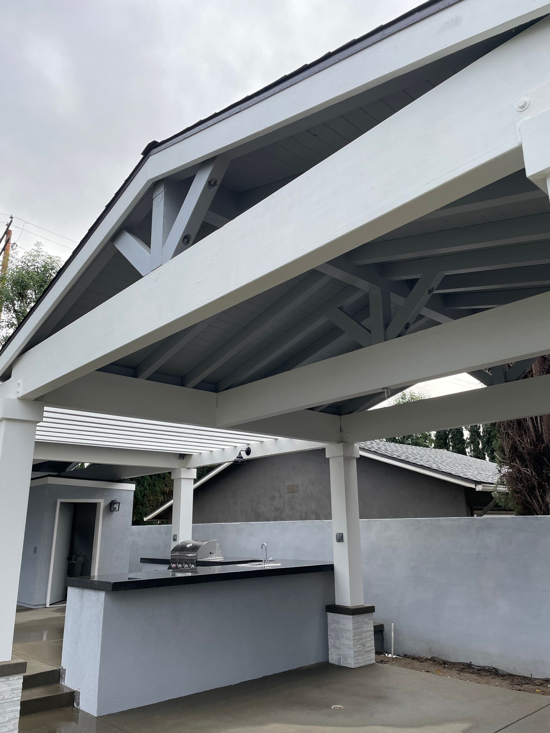 White carport with a gray ceiling, adjacent to a gray concrete bar.