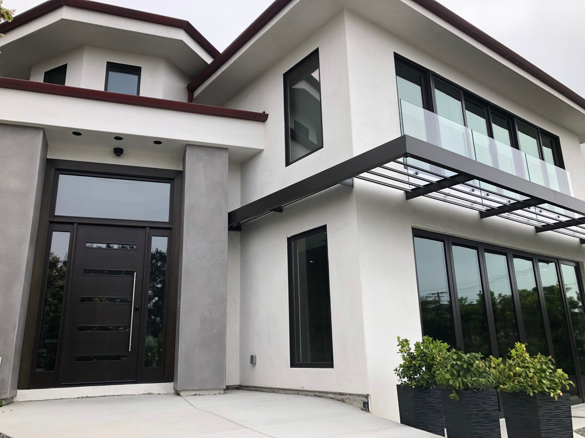 Modern white house with black framed windows and a glass balcony.