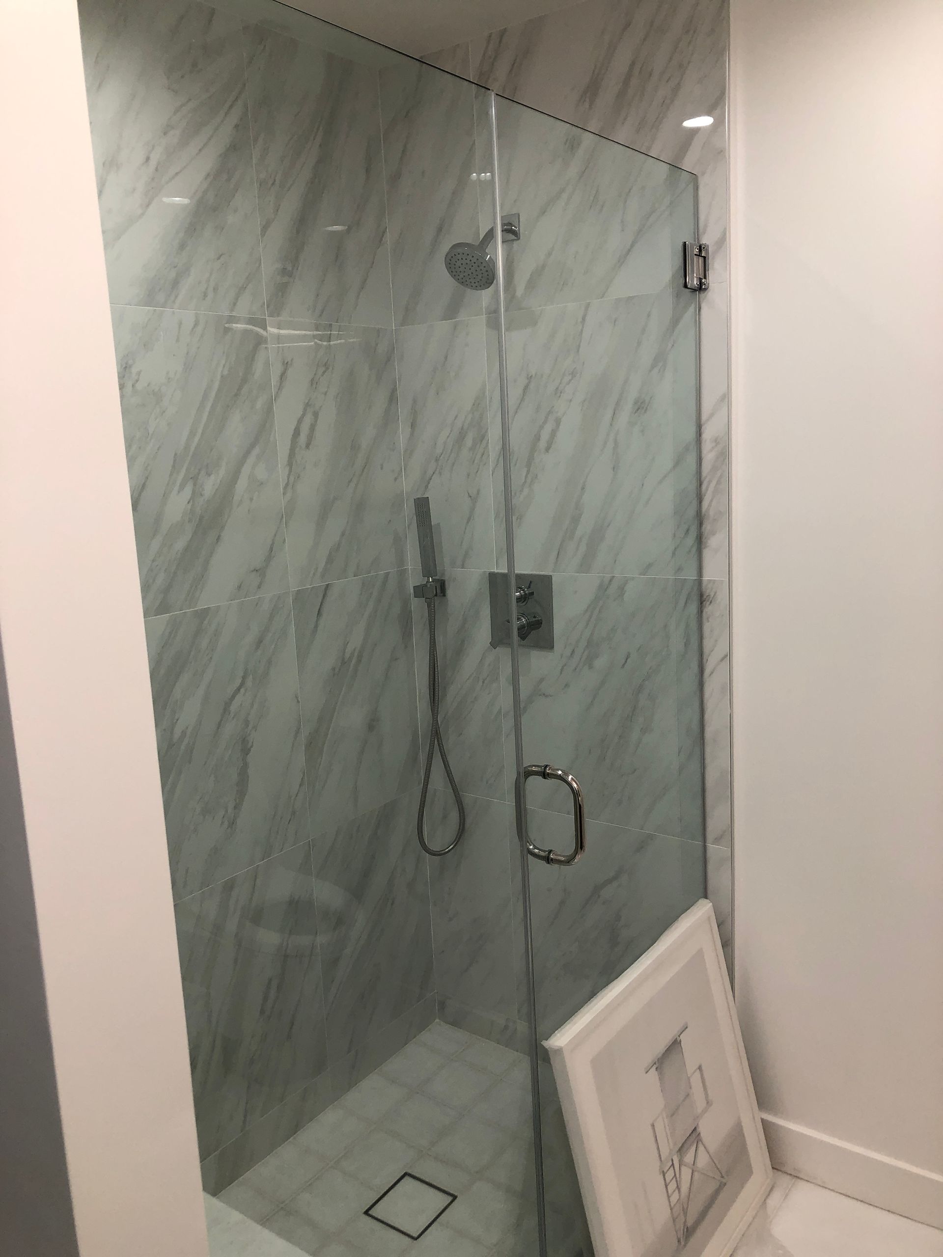 A bathroom with a walk in shower and a picture on the floor.