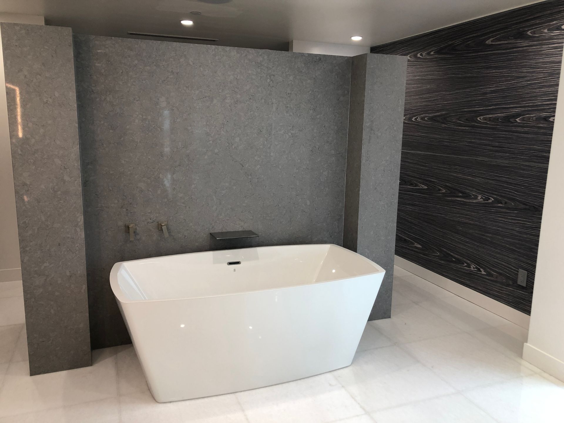 A white bathtub is sitting in a bathroom next to a wall.