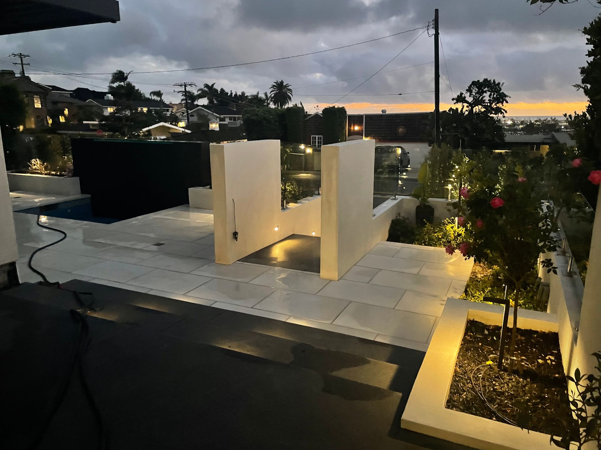 A patio area with a swimming pool and a sunset in the background.