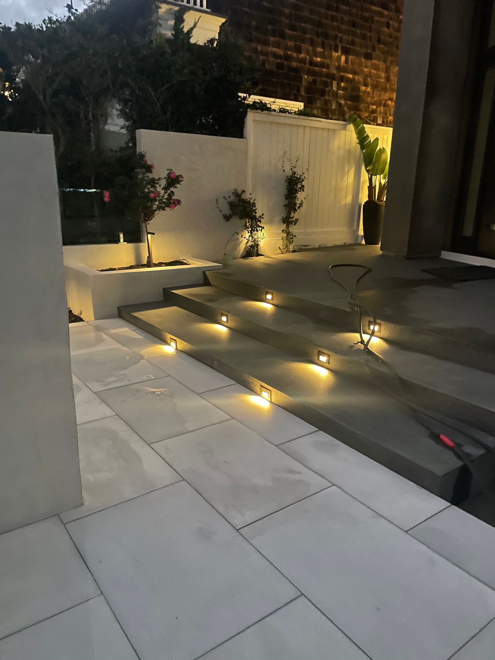 Illuminated stone steps and walkway leading to a building, with small lights embedded in the steps.