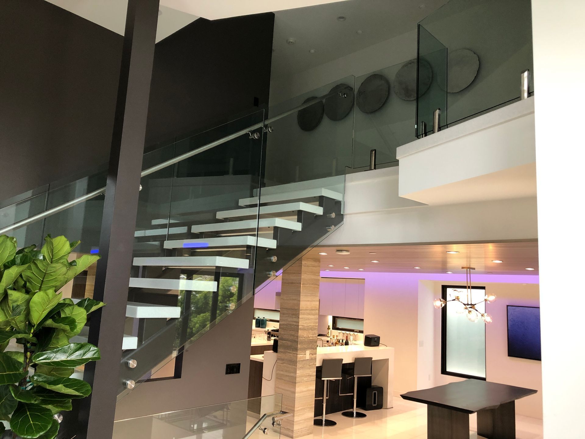 Modern staircase with glass railing. White steps against gray wall. Interior with bar and decor.
