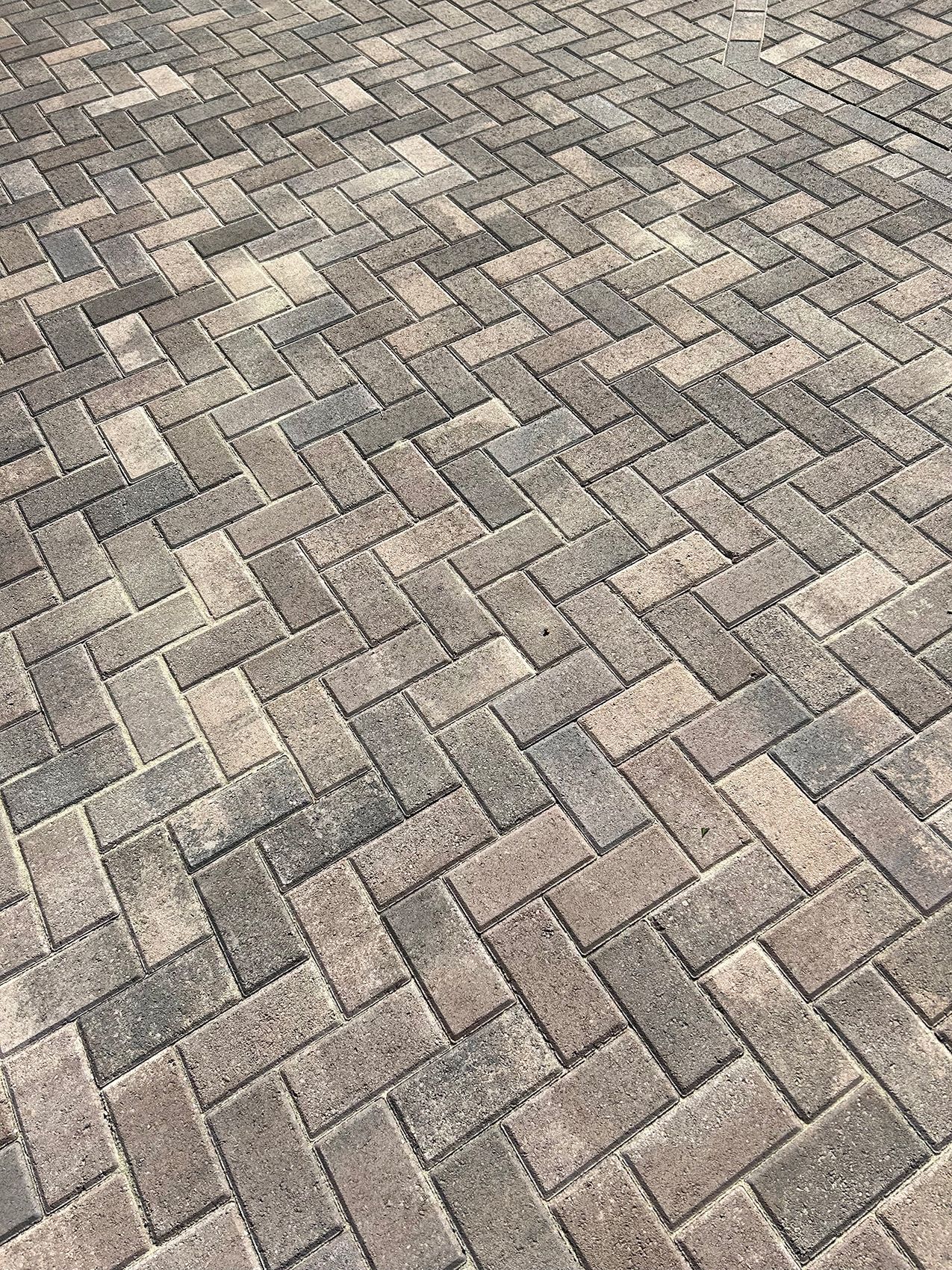 A close up of a brick driveway with a herringbone pattern