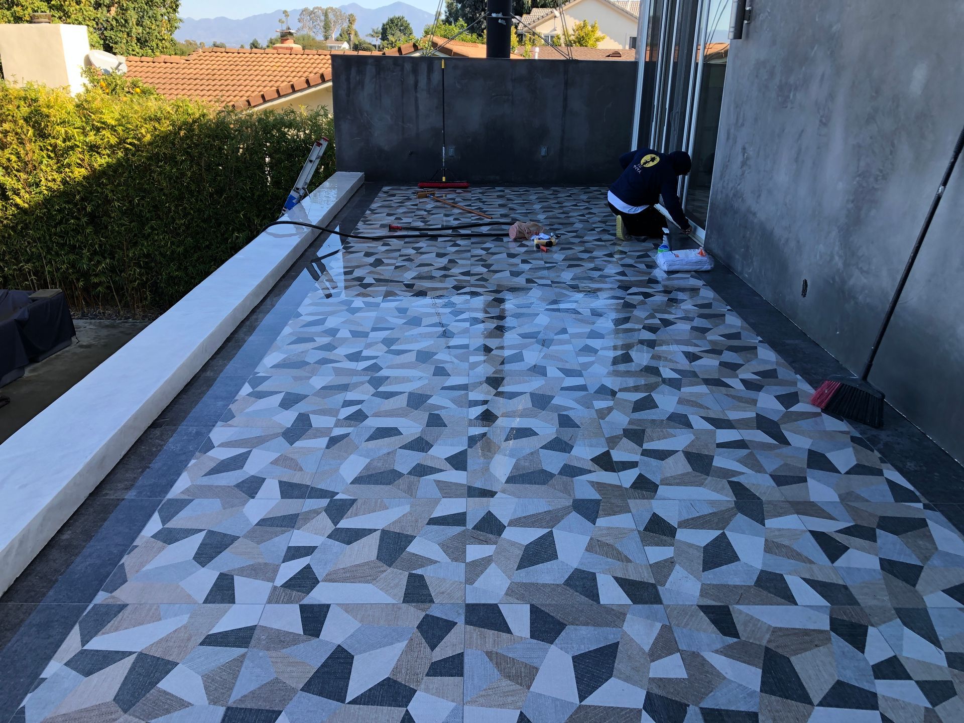 A person is cleaning a tiled floor with a broom.