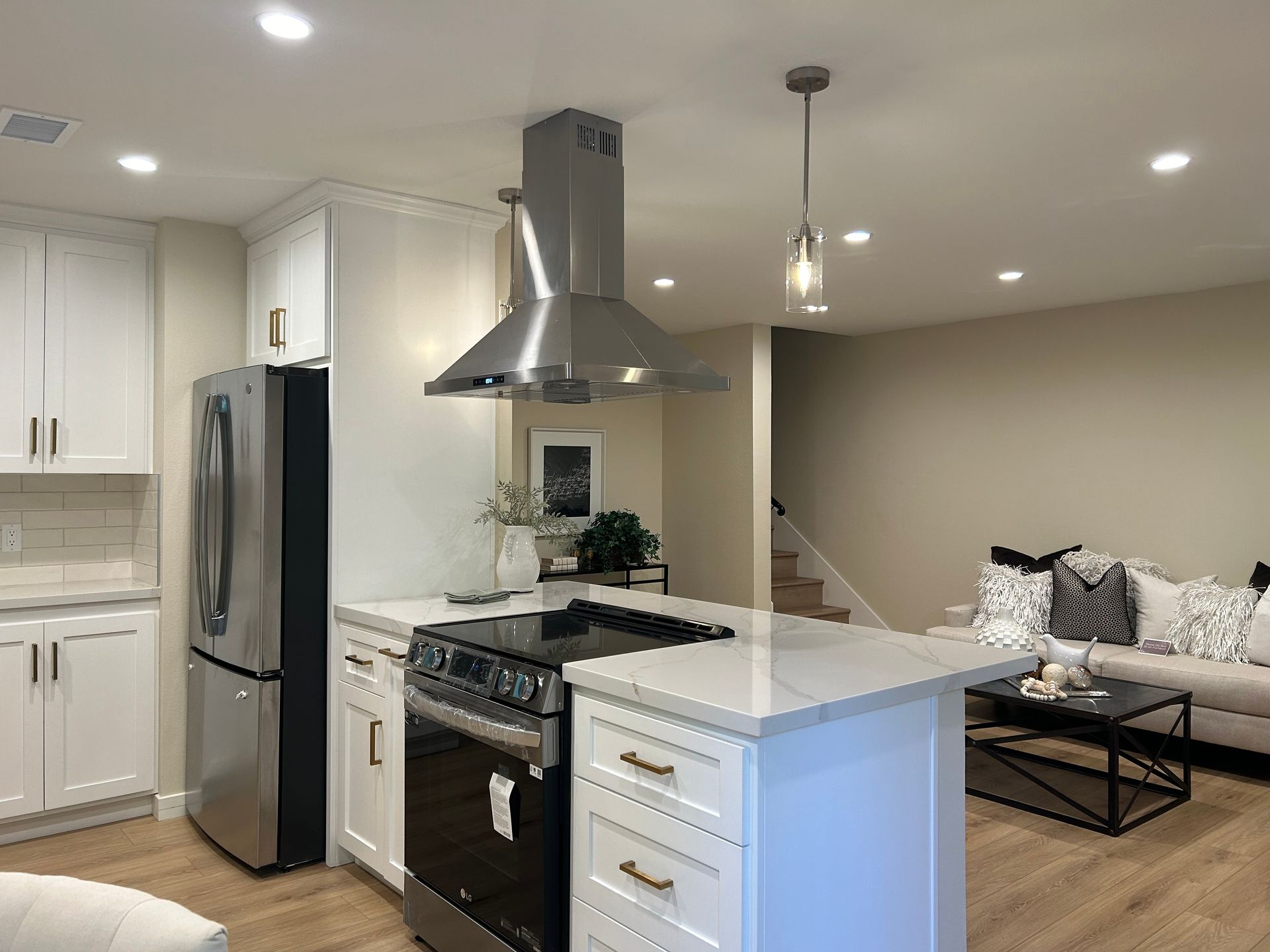 A kitchen with white cabinets , stainless steel appliances , a refrigerator and a stove.