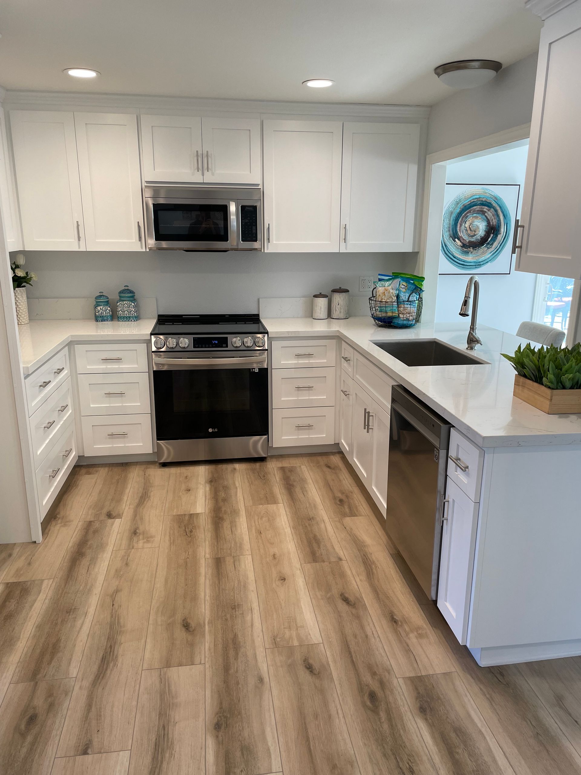 A kitchen with white cabinets , stainless steel appliances , a sink , and a stove.
