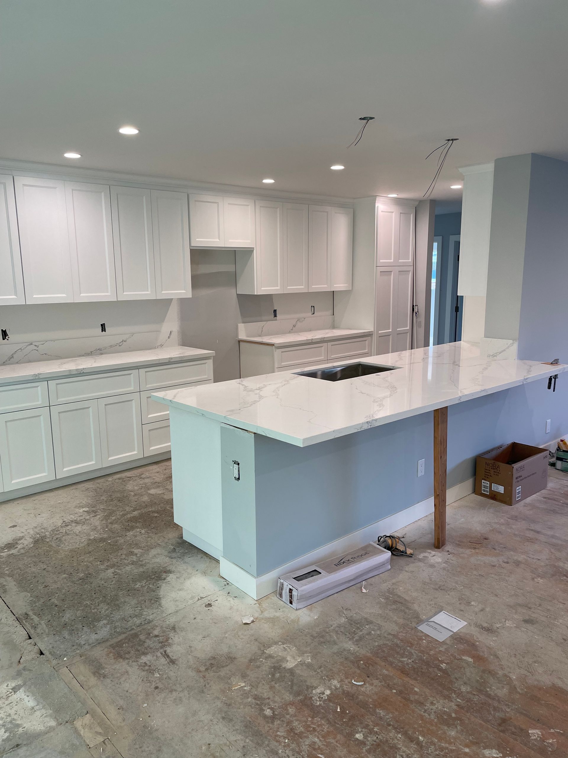 A kitchen with white cabinets and a large island in the middle
