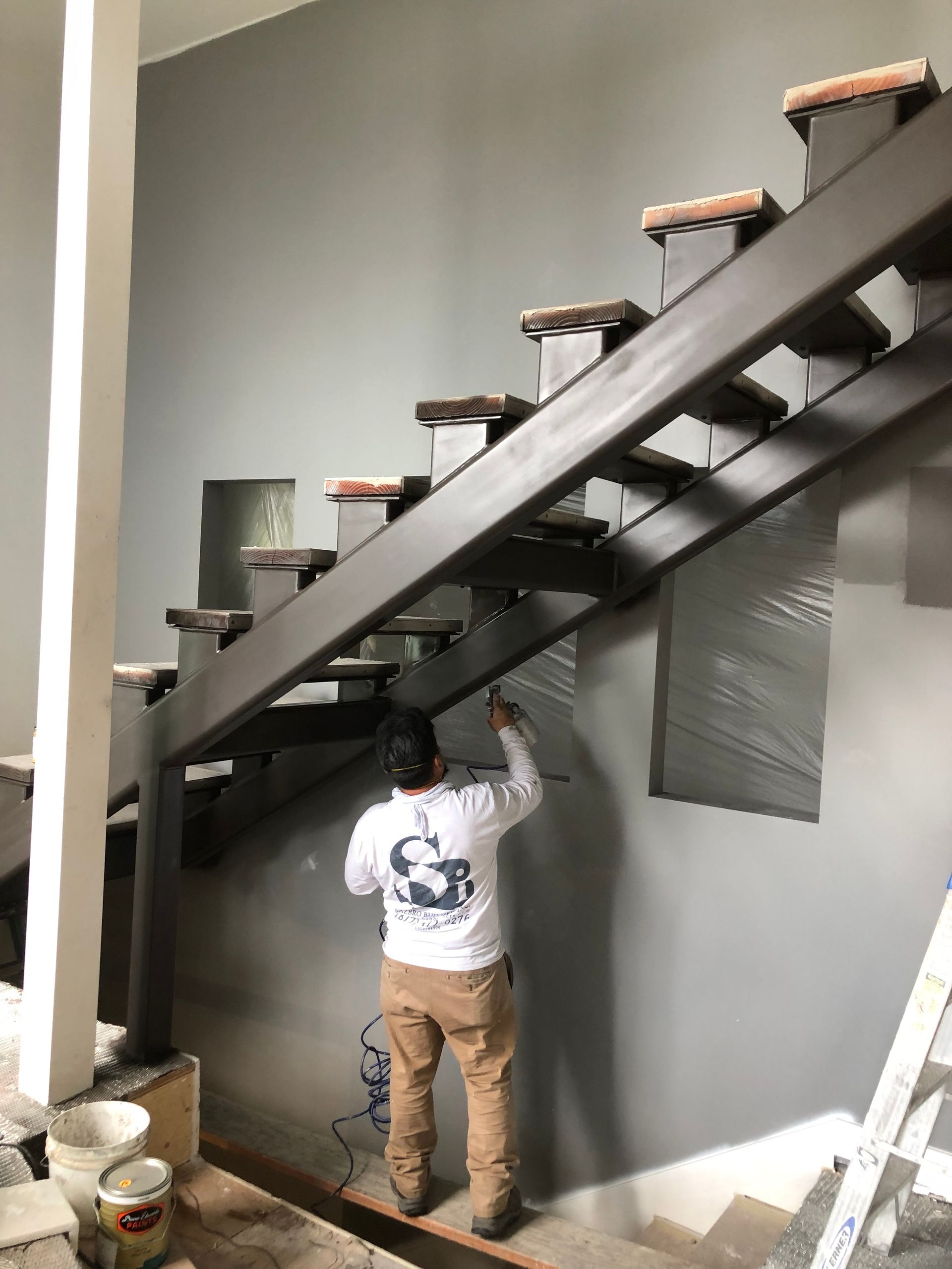 A man is painting a wall next to a staircase.