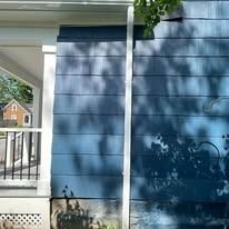 Blue horizontal siding on a house exterior features a white corner trim piece and a partial view of a porch.