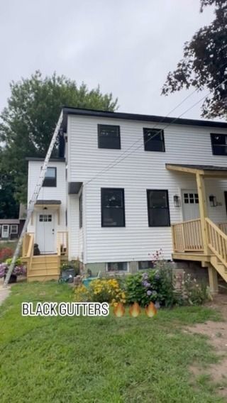 A two-story white house with new black windows and gutters, featuring two front entrances with light wood stairs.