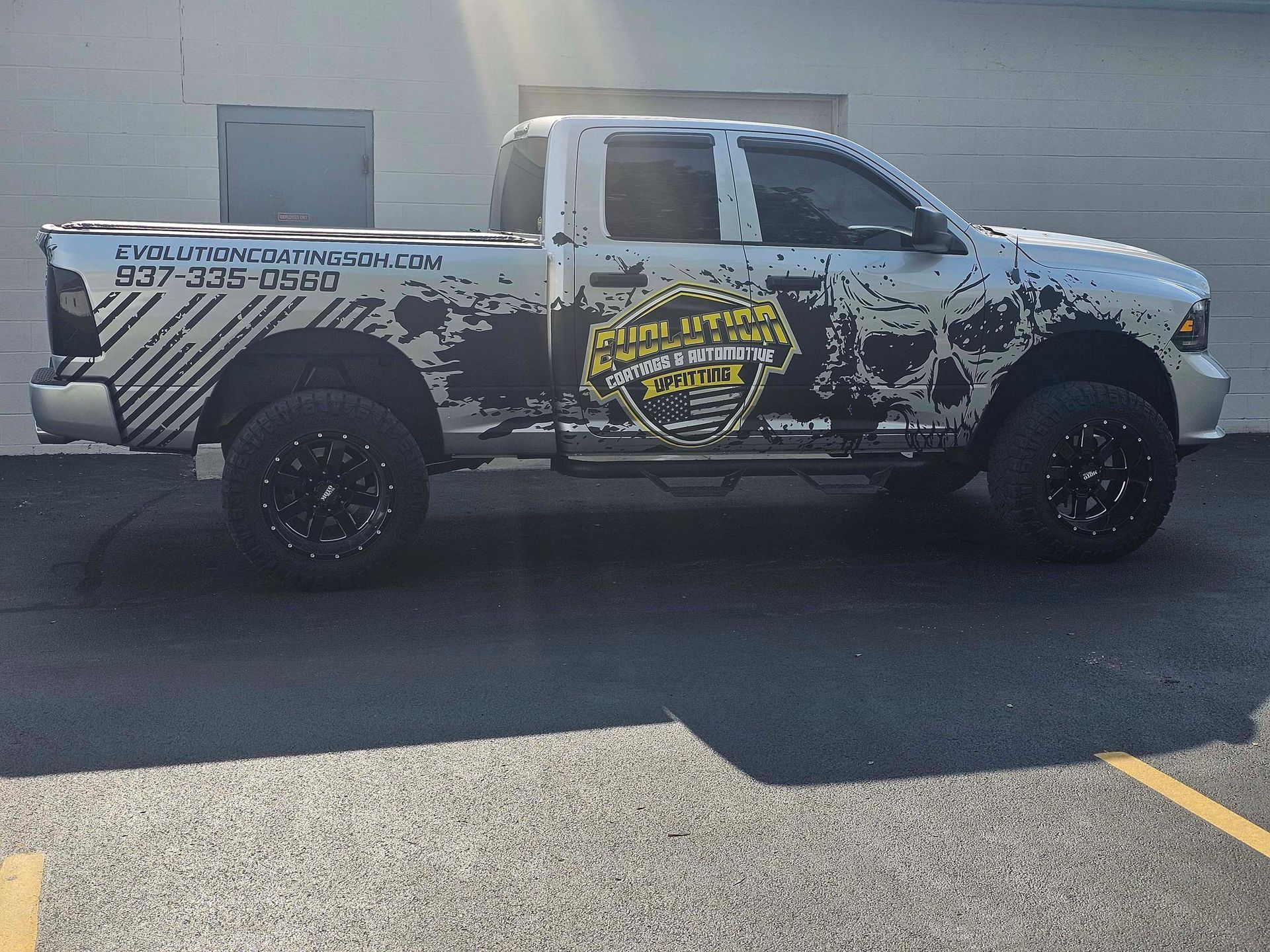 A white truck with a skull on the side is parked in a parking lot.