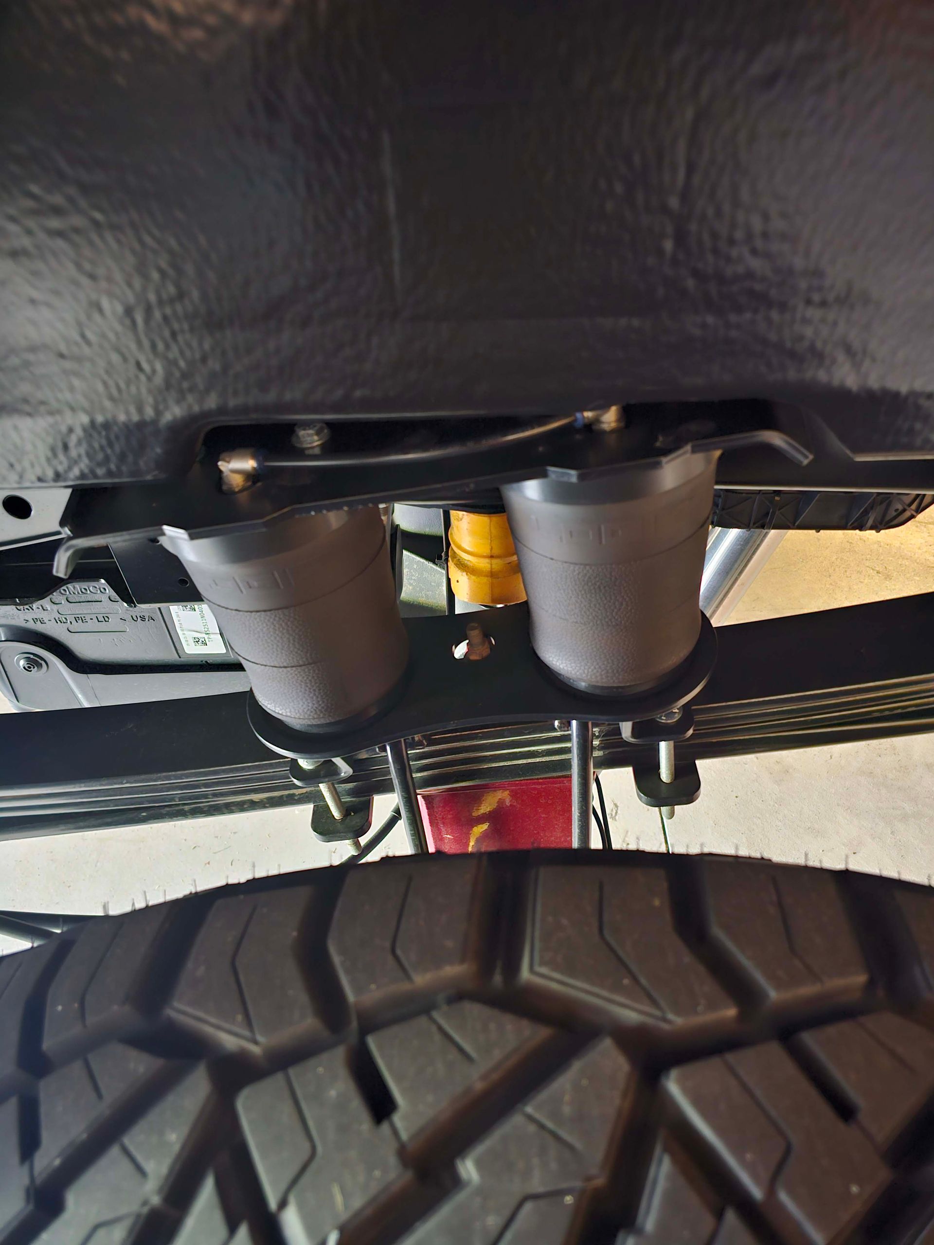 A close up of the underside of a truck with a tire in the foreground.