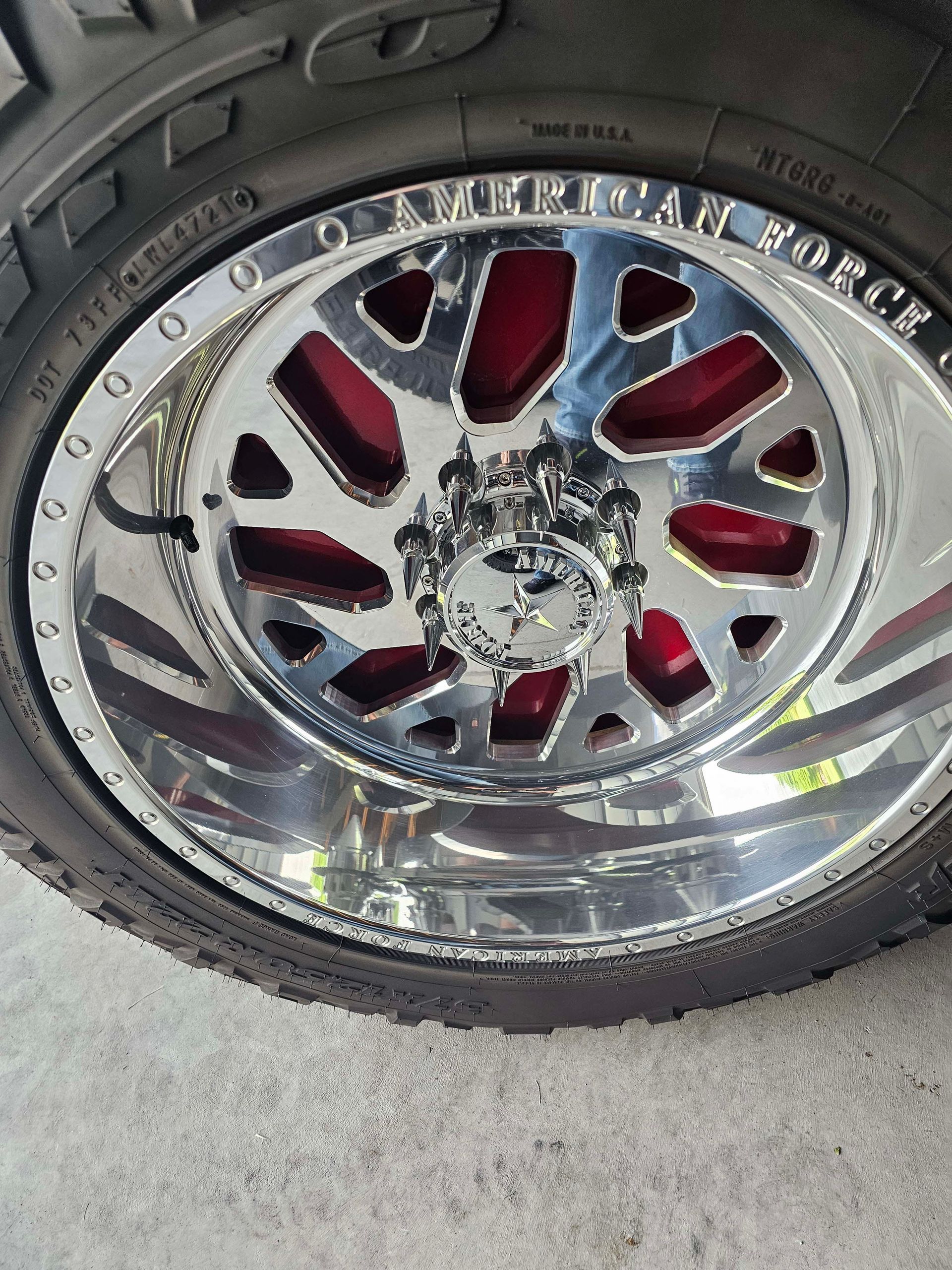 A close up of a chrome wheel on a tire that says american force