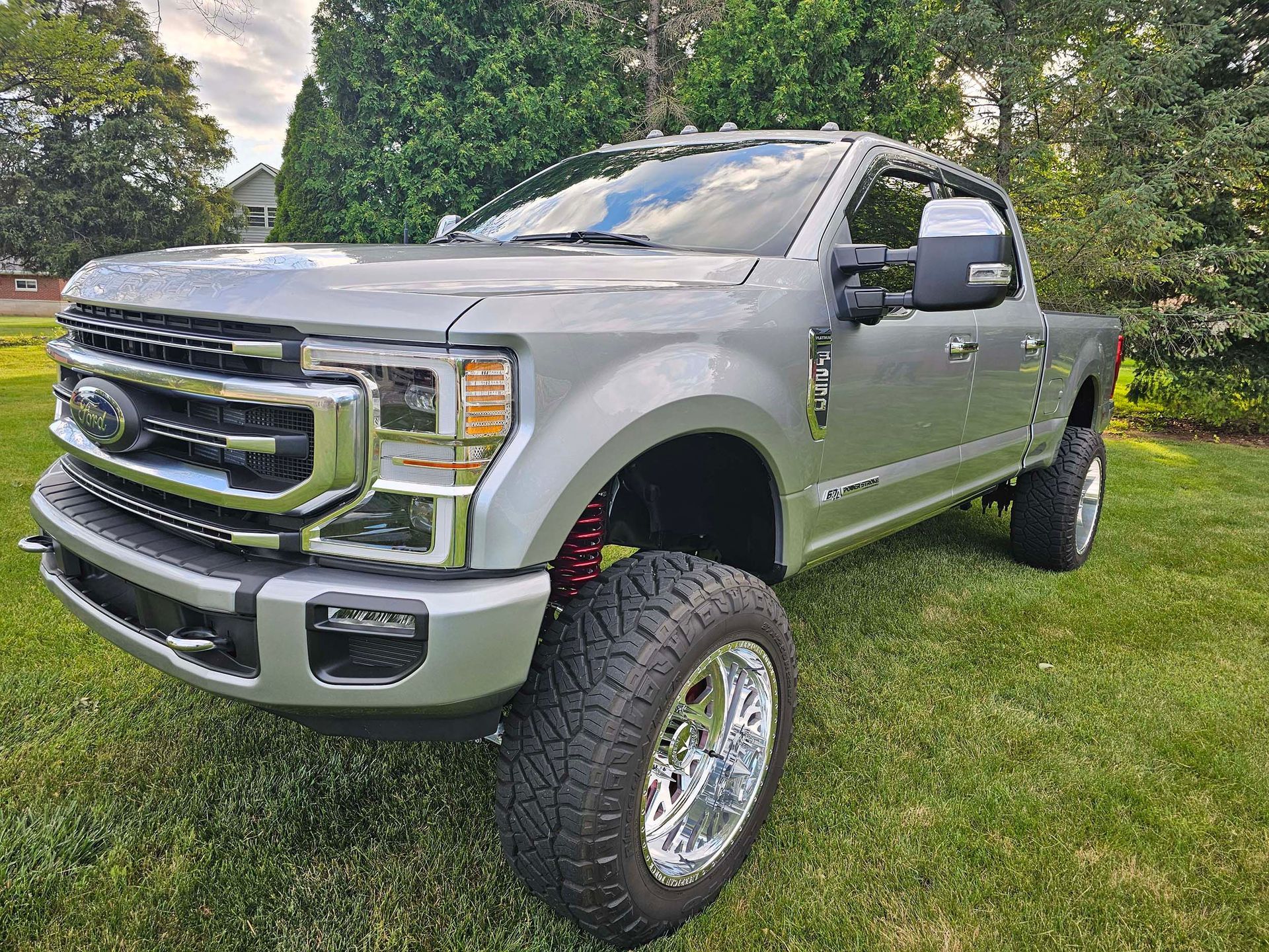 A silver ford f250 pickup truck is parked in the grass.