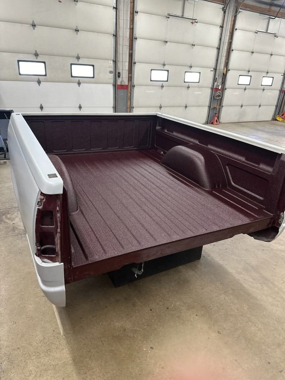 A red truck bed is sitting in a garage.