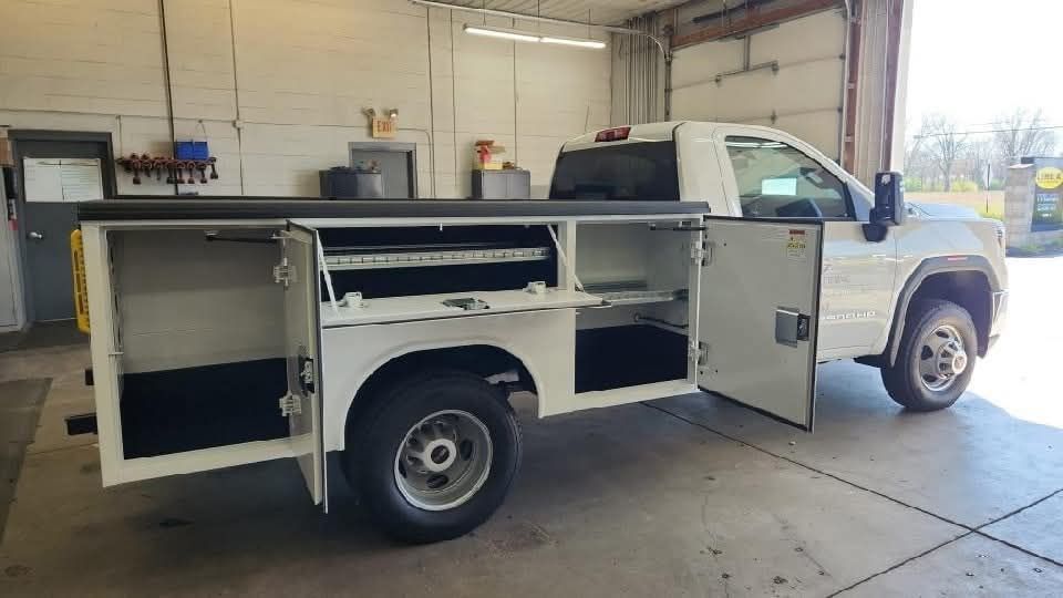 A white truck with its doors open is parked in a garage.