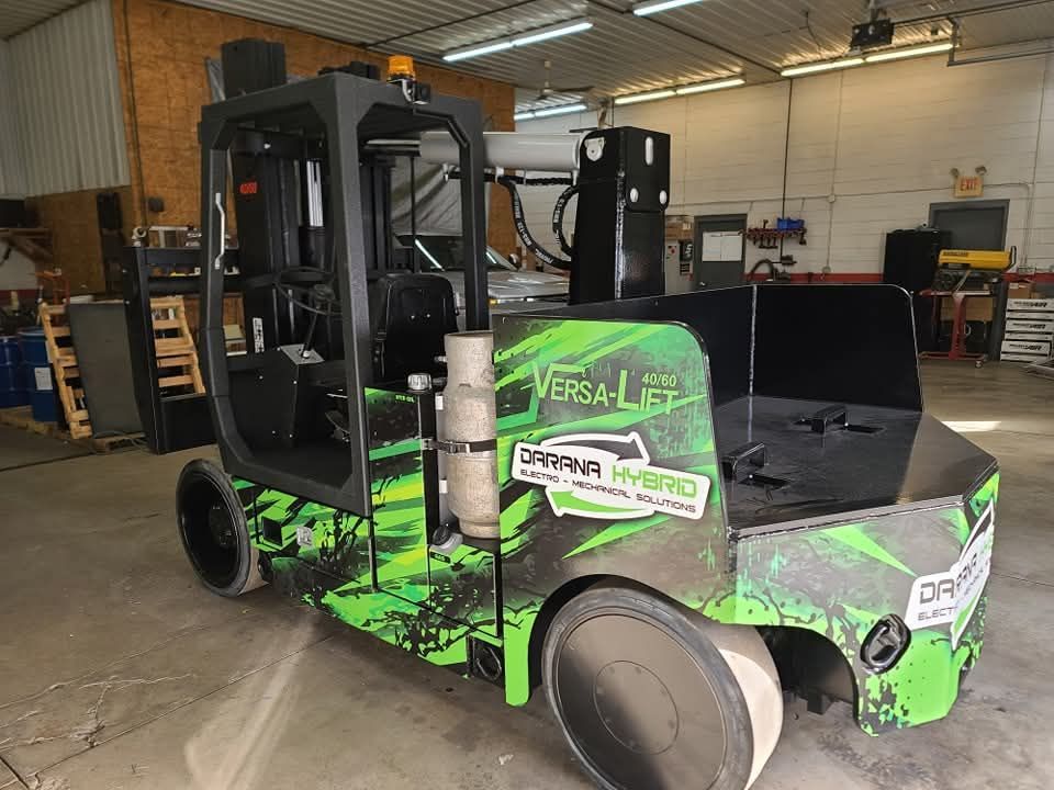 A green and black forklift is parked in a garage.