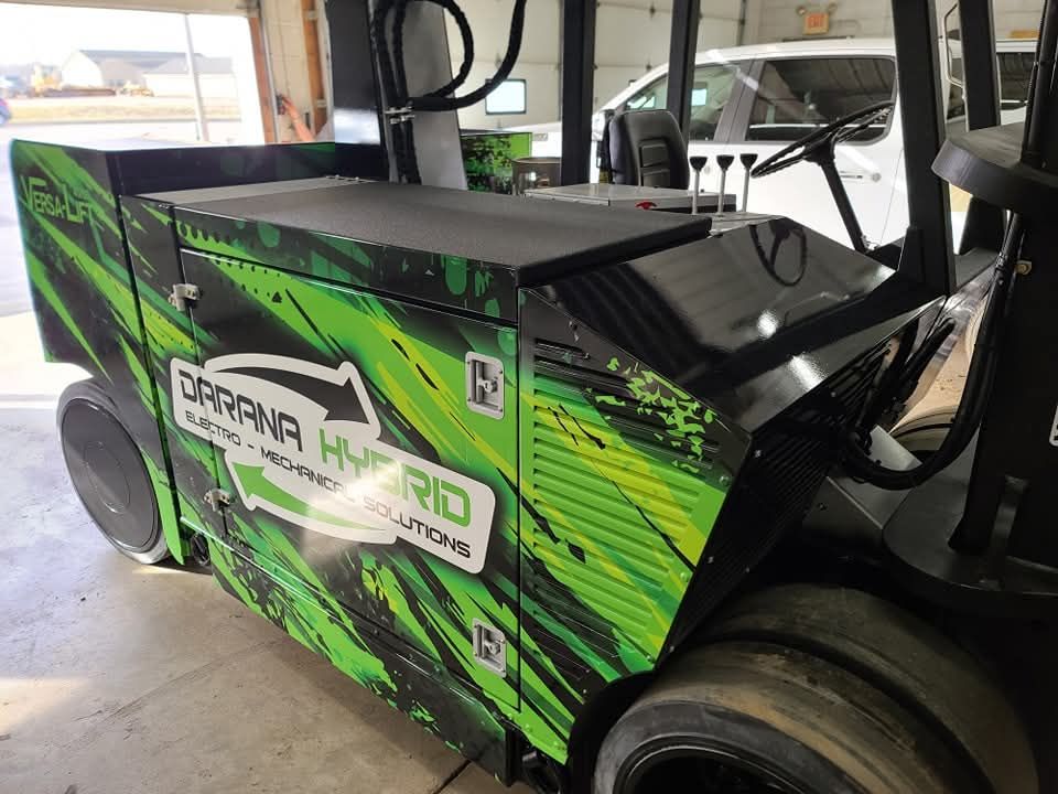 A green and black forklift is parked in a garage.