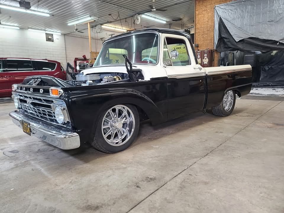 A black and white pickup truck is parked in a garage.