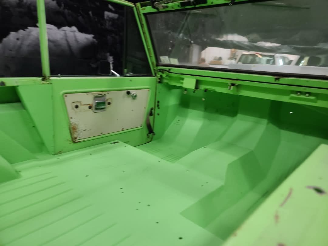 The inside of a green vehicle with a white door.