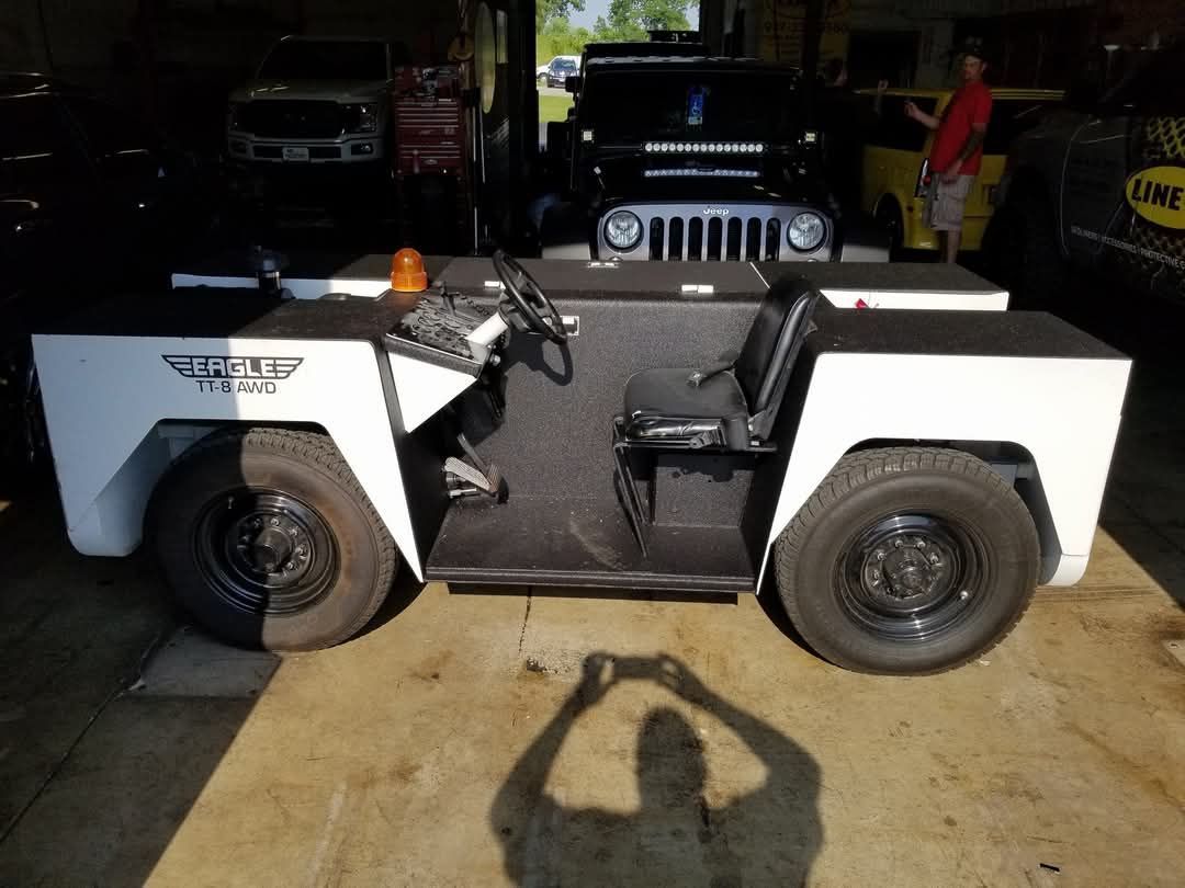 A jeep and a golf cart are parked in a garage