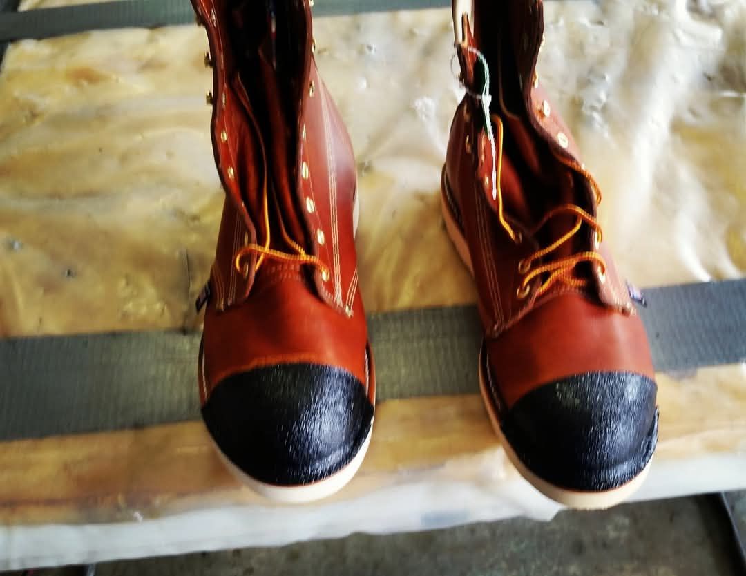 A pair of brown boots with black soles are sitting on a table