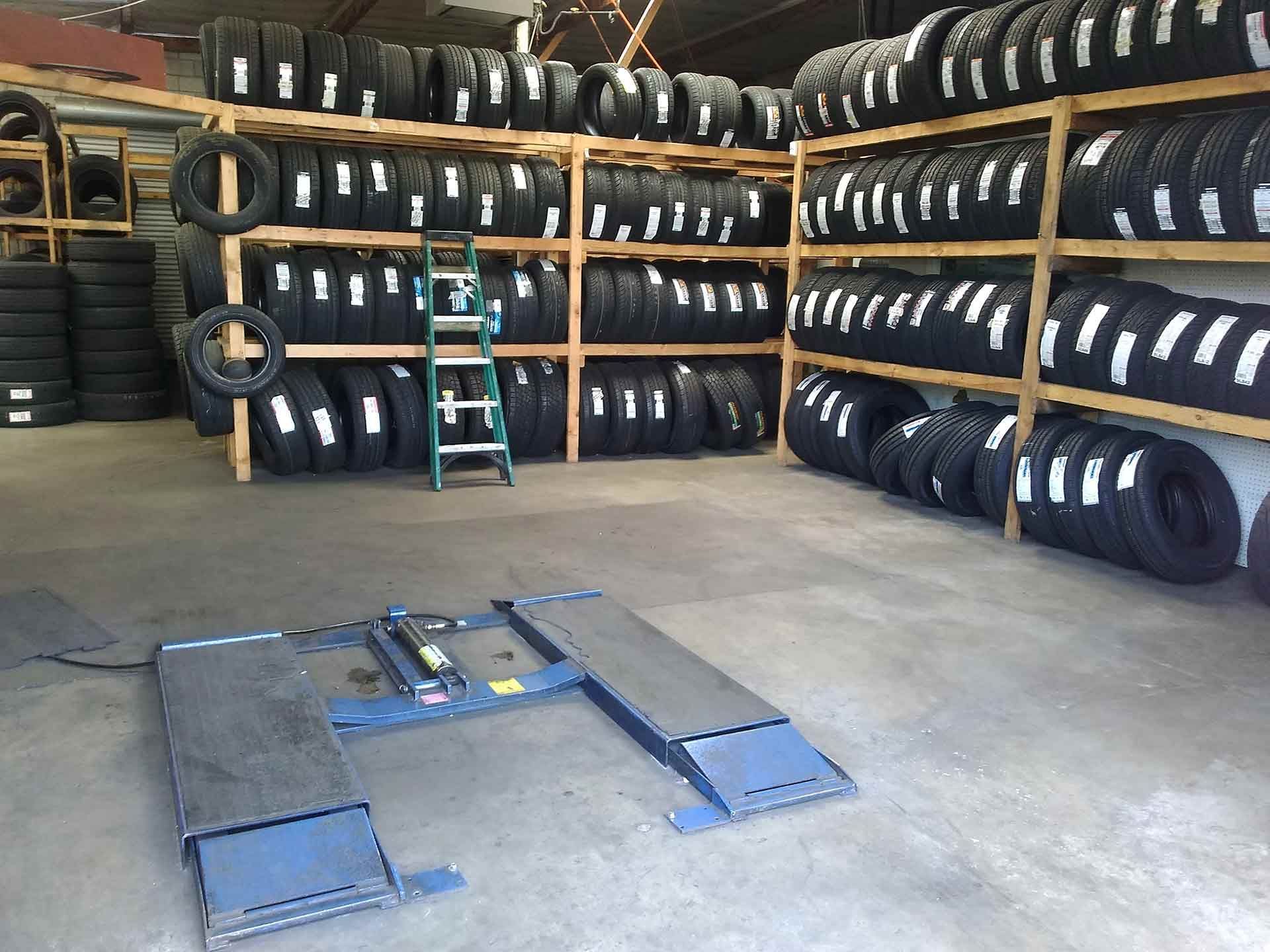 Tire shop interior: tires on shelves, vehicle lift in front.