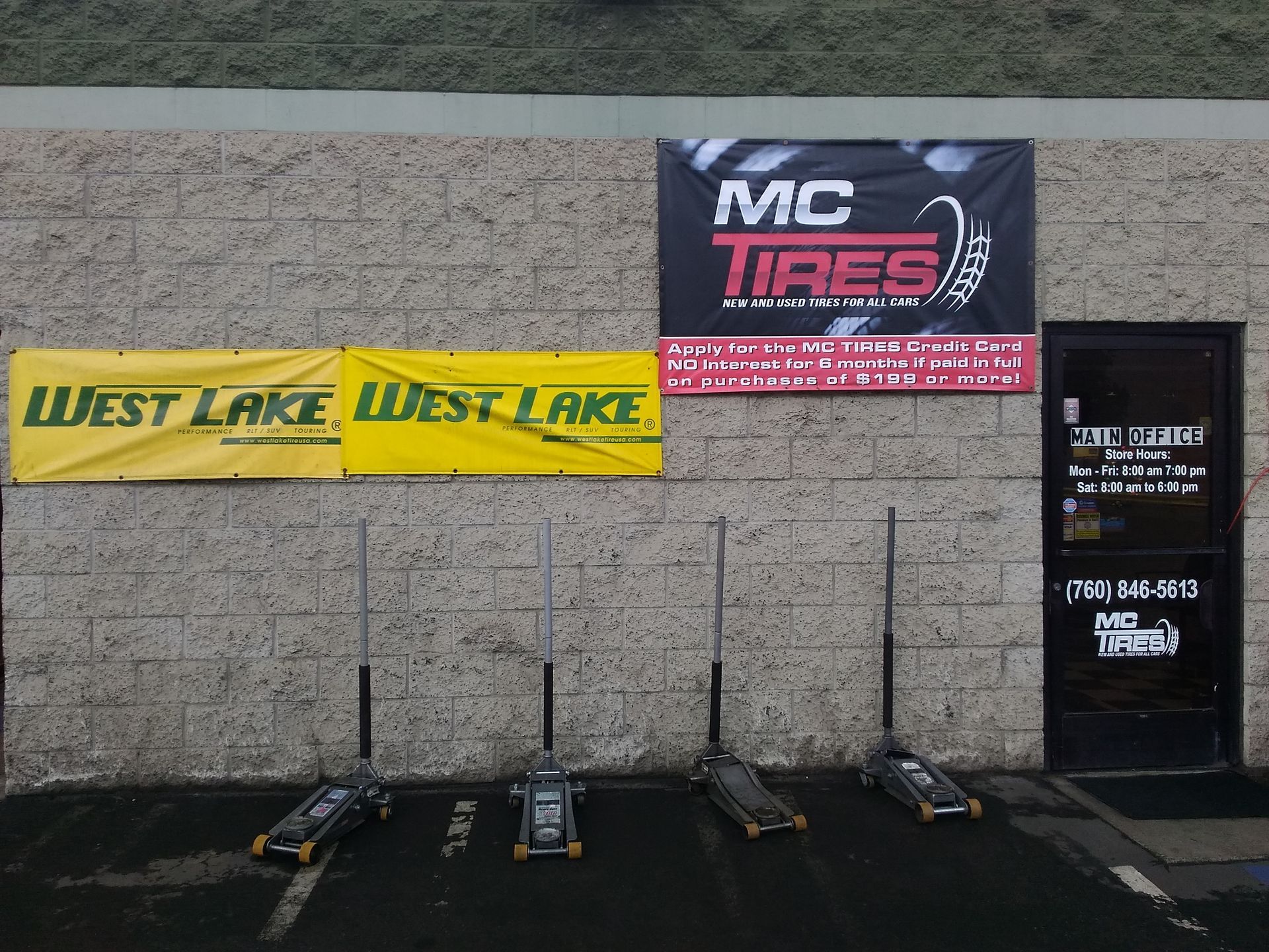 Exterior of MC Tires shop with four jacks lined up. Yellow and black signage is visible.