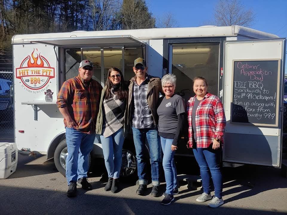 Five people pose in front of a food trailer, 