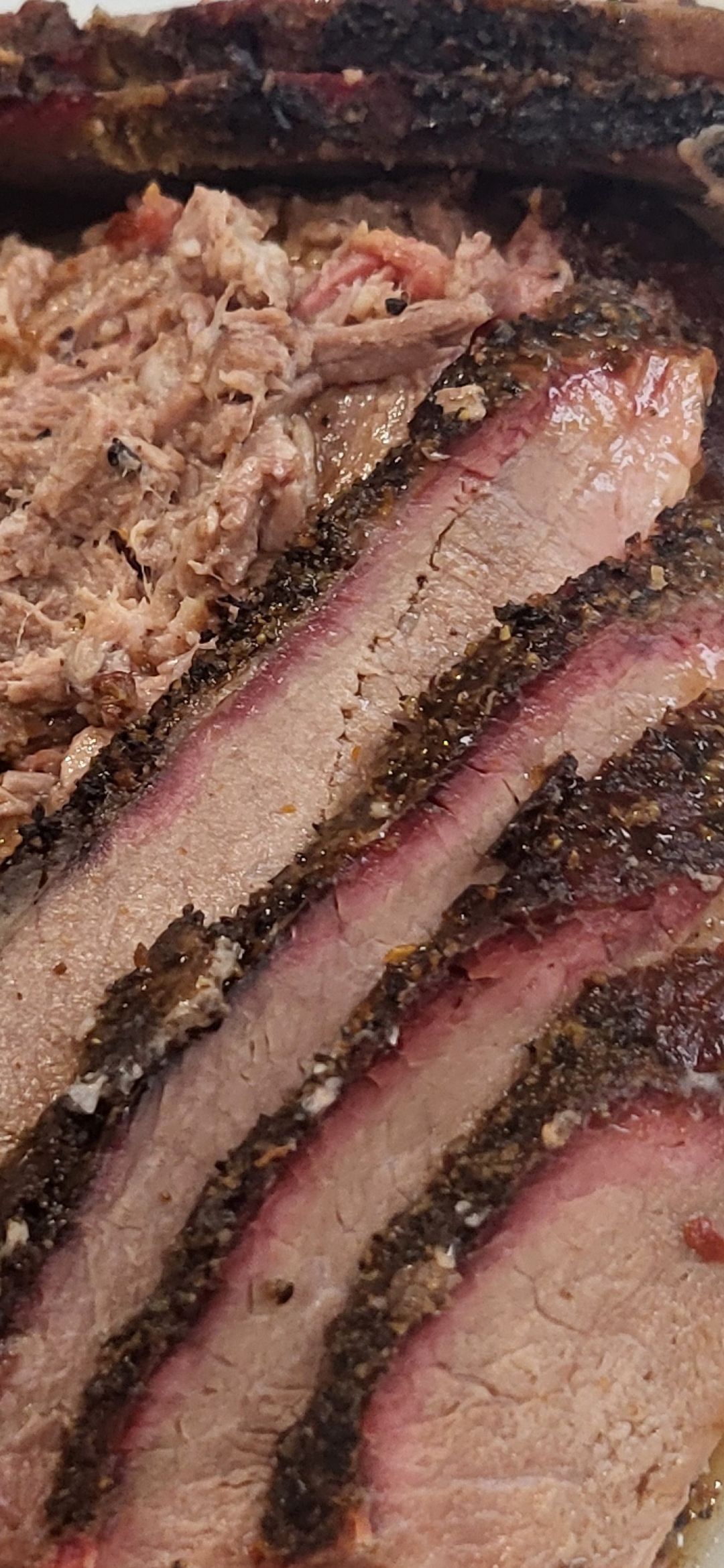 Sliced smoked brisket with a red smoke ring and pulled pork.
