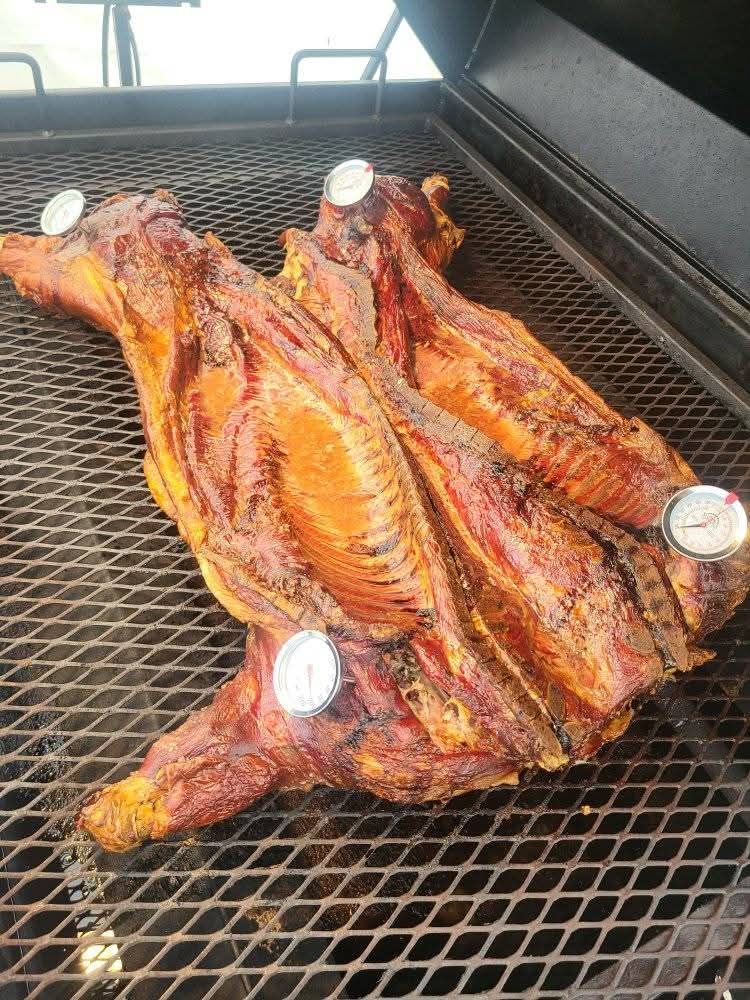 Smoked meat on a grill with three temperature gauges.