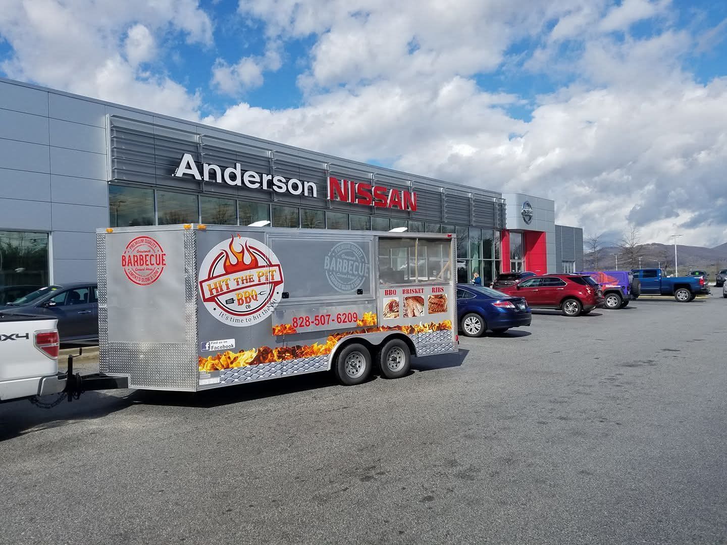 Food truck parked outside an Anderson Nissan dealership on a sunny day.