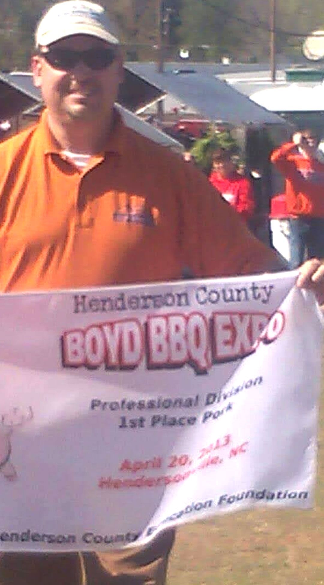 Man holding a banner for the Henderson County Boyd BBQ Expo, 1st place winner.