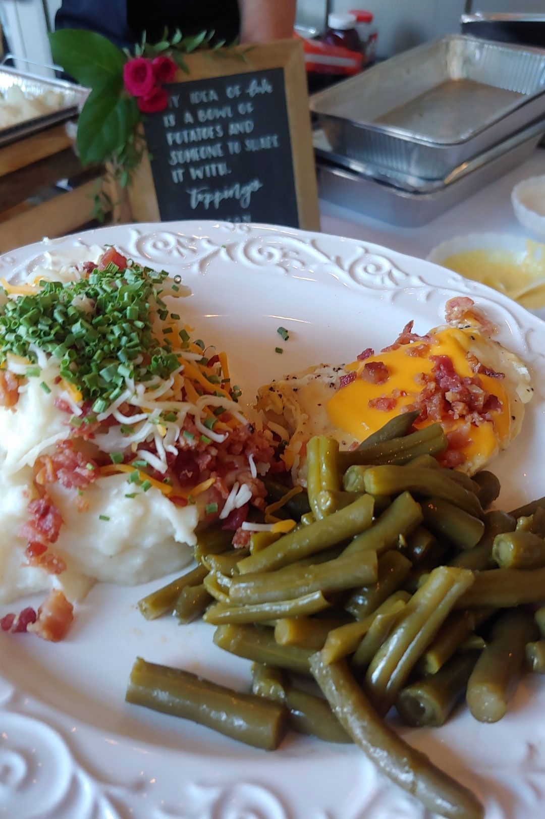 Plate of food: mashed potatoes with bacon and cheese, green beans, and a fried egg.