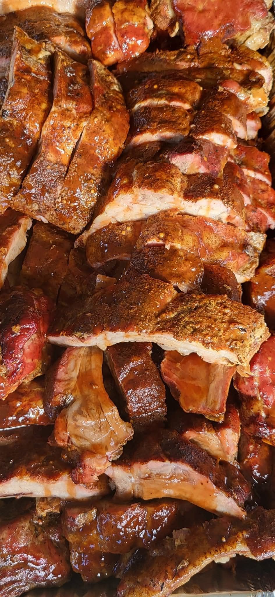 Close-up of cooked meat, likely ribs or brisket, with a dark, seared exterior.